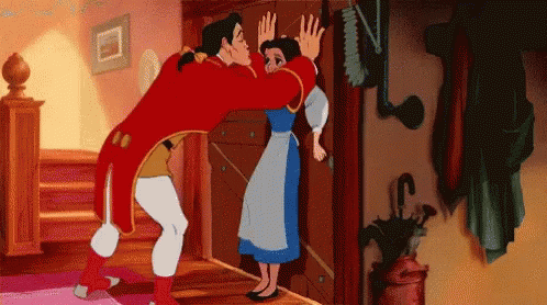 The image shows a scene from Disney's Beauty and the Beast where Gaston aggressively corners Belle against a door. Gaston is leaning in close while Belle looks uncomfortable, pushing him away, emphasizing her rejection of his advances and highlighting Gaston's arrogance.